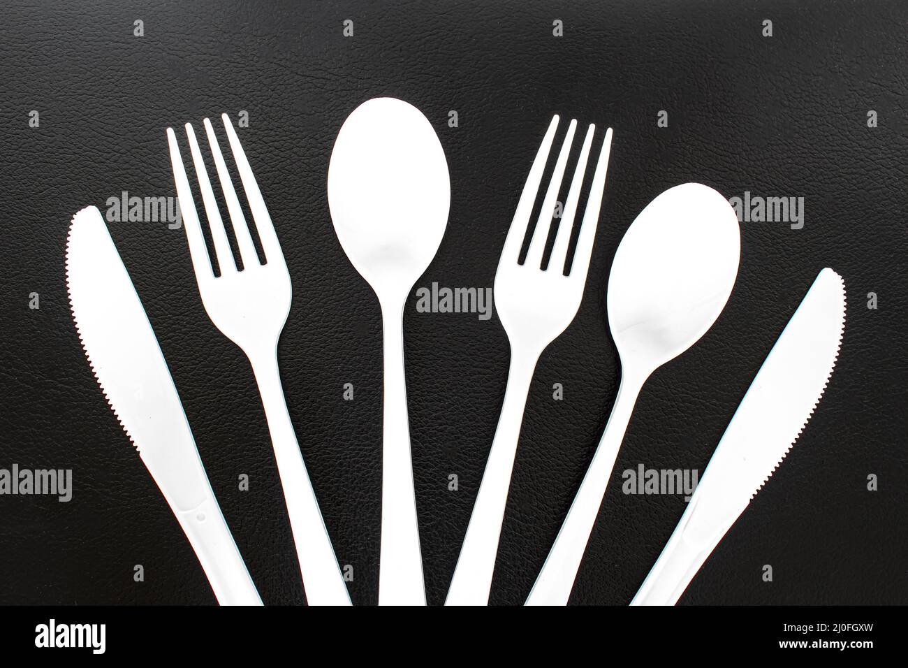 Single use white plastic cutlery on a leather background. Concept: Ban single use plastic Stock Photo