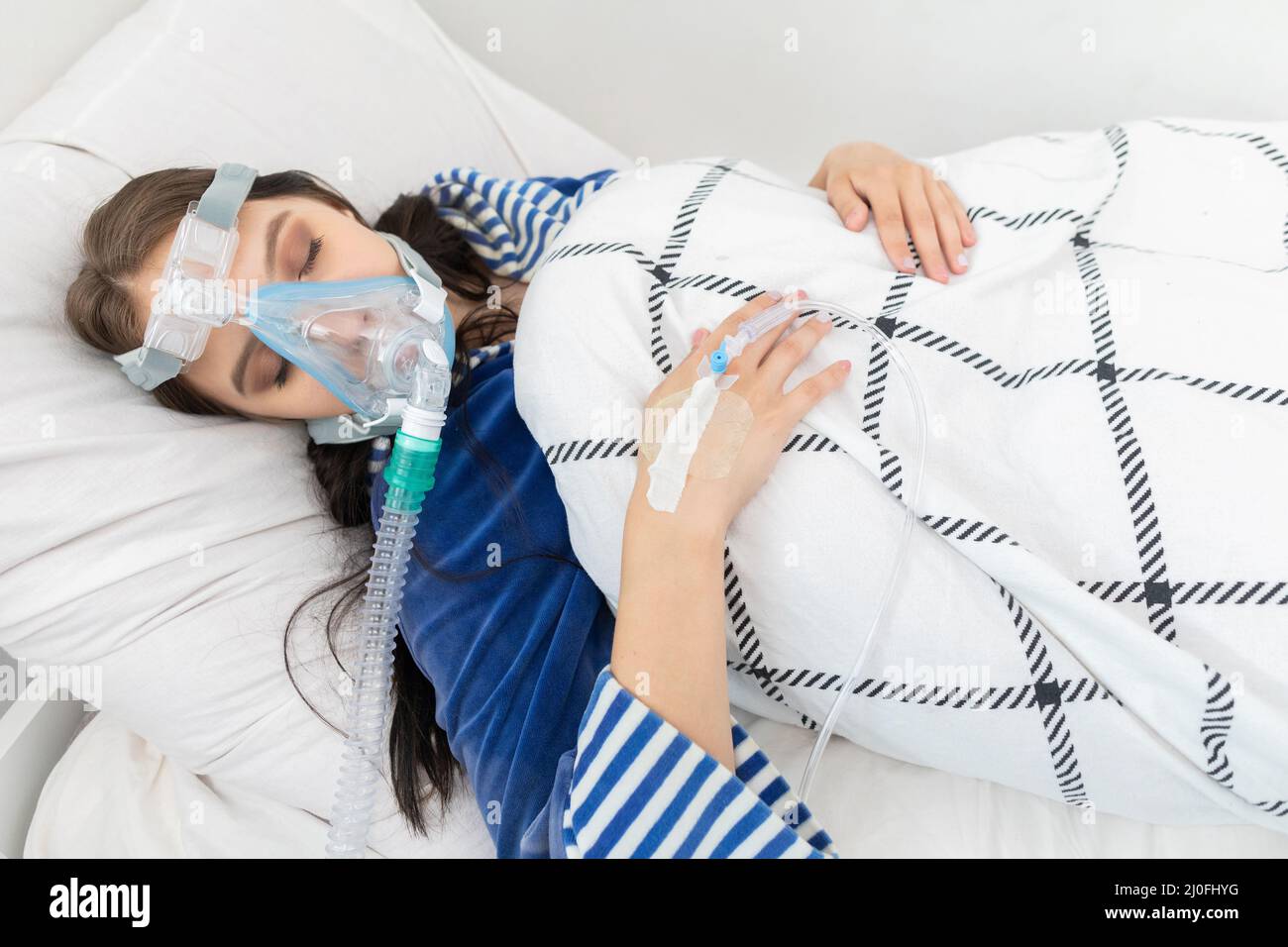 Seriously ill teenager connected to a respirator to support breathing. COVID-19 infection. Stock Photo