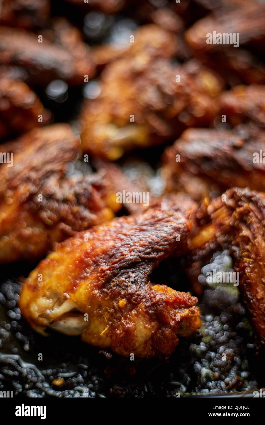 Grilled chicken wings in spices in black metal baking tray on stone