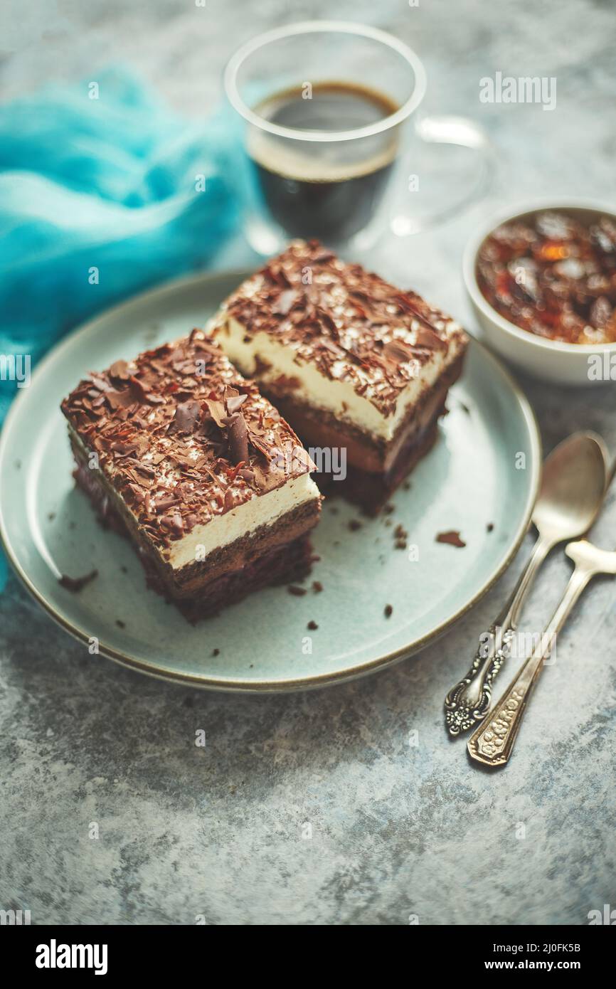 Delicious chocolate cake with layers served on ceramic blue plate. With cup of fresh black coffe Stock Photo