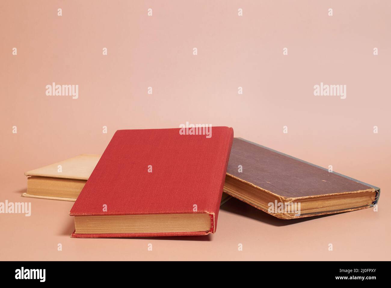 A stack of old worn books on a colored background Stock Photo