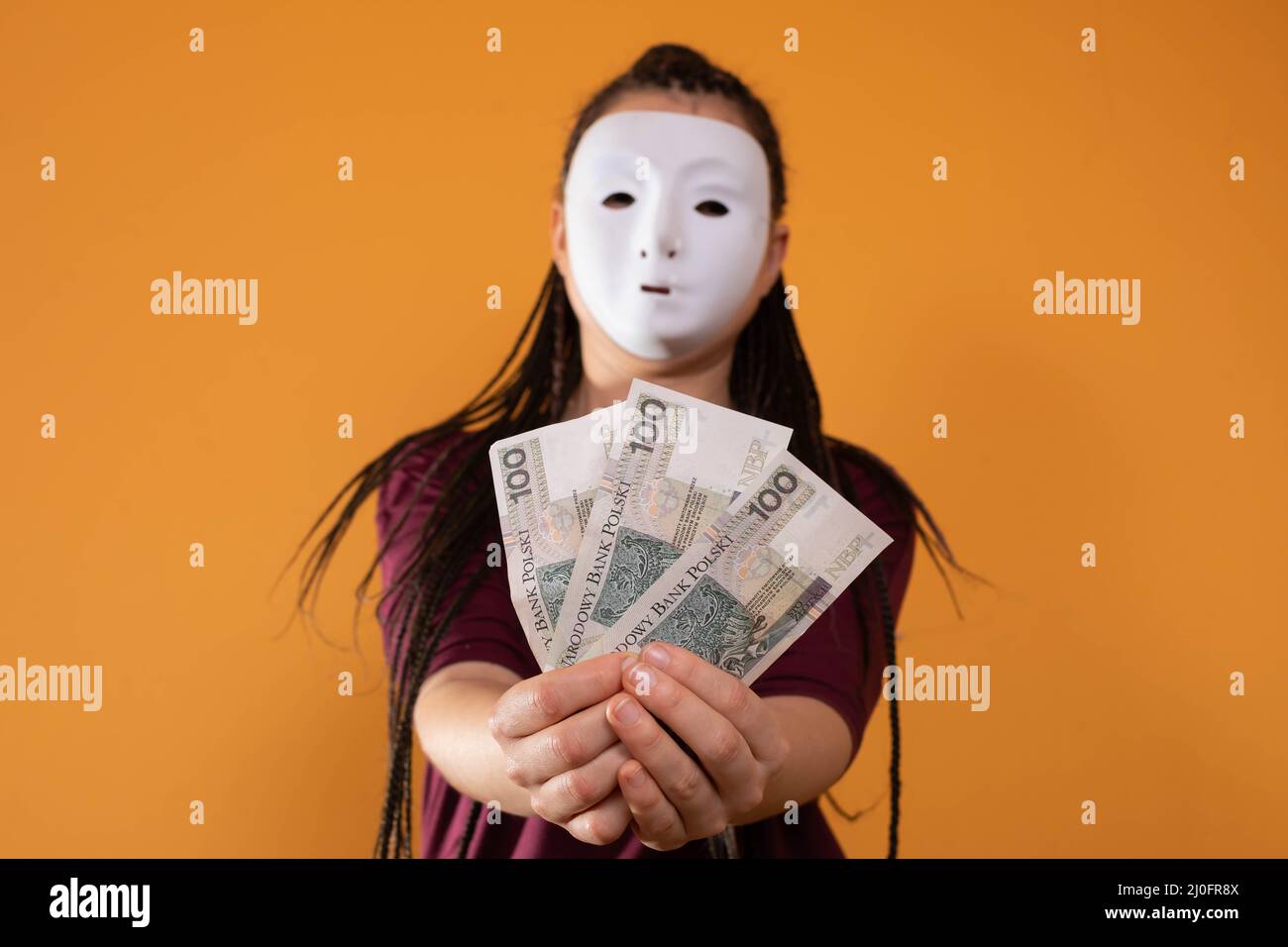 An anonymous woman stands and pulls her hand in with paper banknotes with the face value of one hundred Polish zlotys. No face b Stock Photo