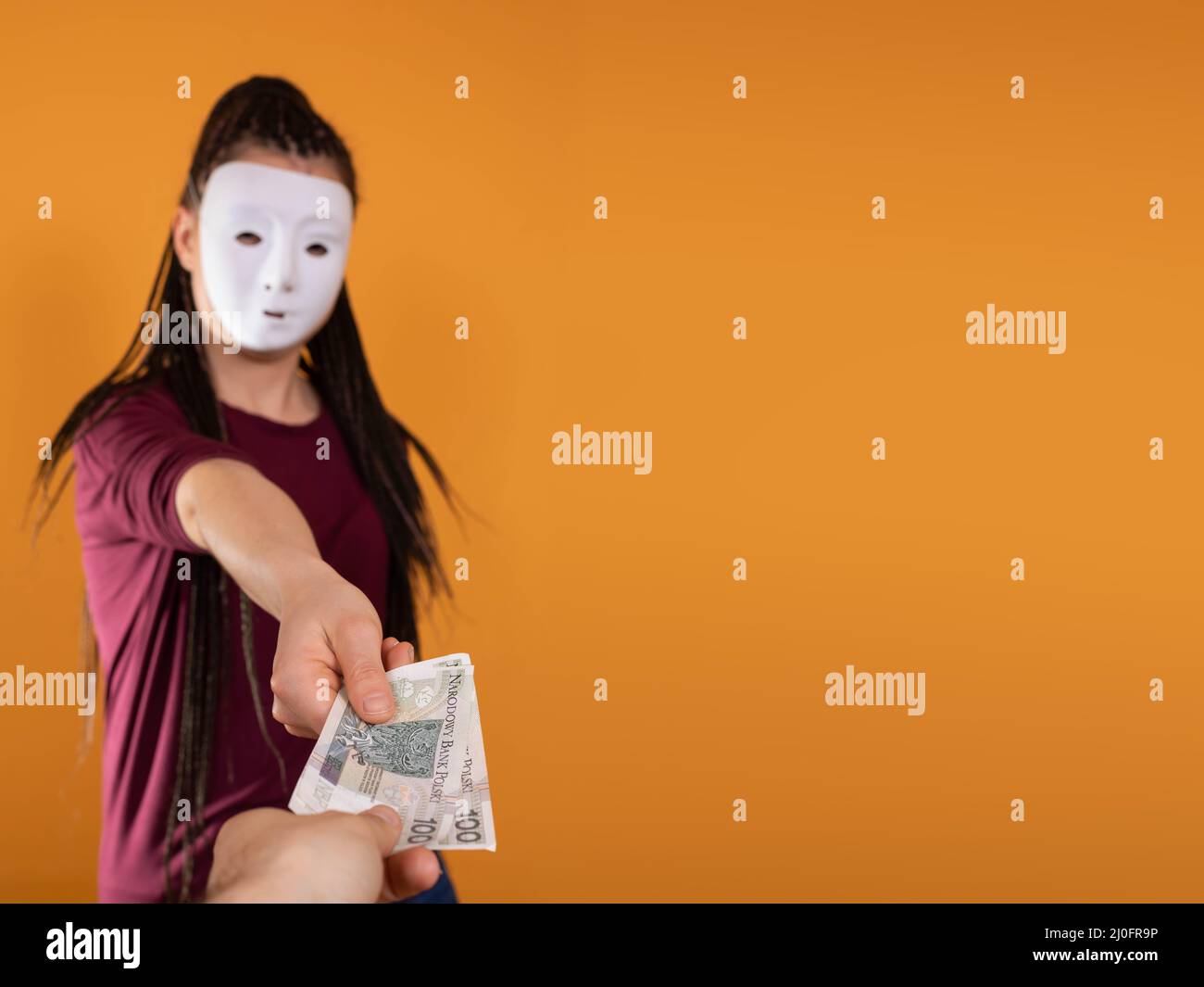 An anonymous woman stands and pulls her hand in with paper banknotes with the face value of one hundred Polish zlotys. No face b Stock Photo