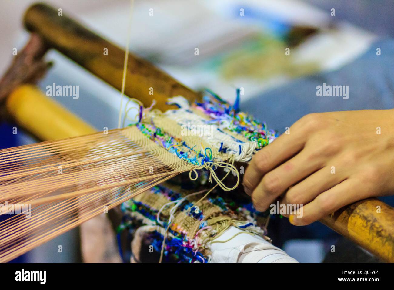 Weaver using small loom or weaving machine for weaving fabric. Weaver is weaving show and teaching to the tourist at the night m Stock Photo