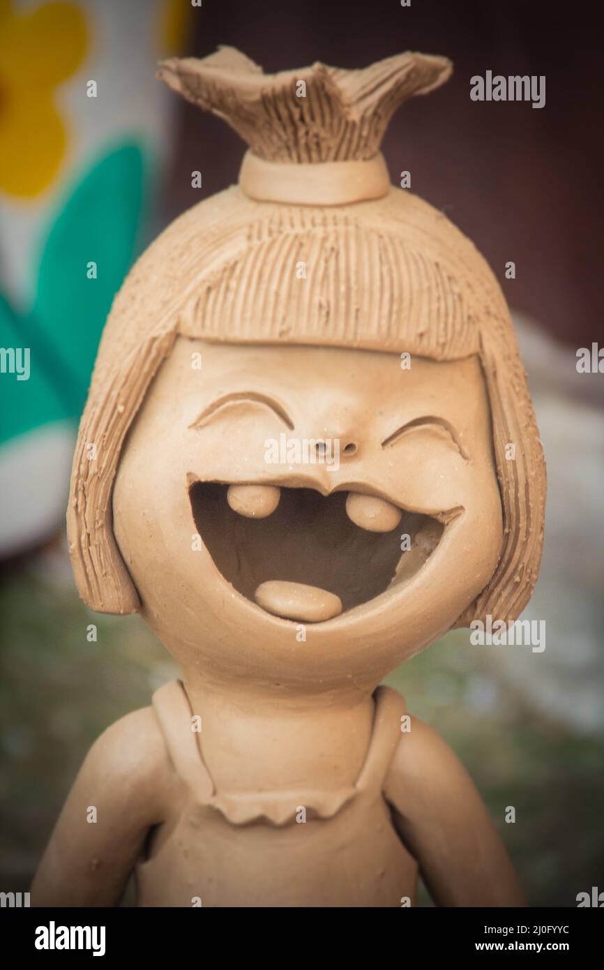 Happy Ceramic dolls for garden decoration. Cute ceramic clay pottery of girl show her up-swept bun and broken tooth that happy l Stock Photo