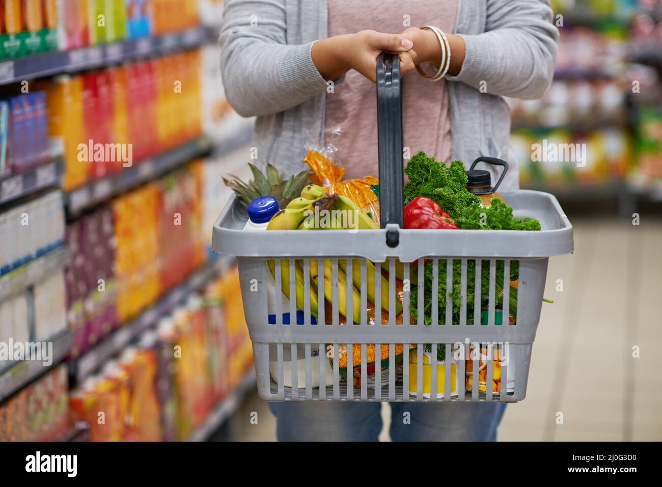 Filling up on some freshness. Closeup shot of a woman holding a basket full of groceries in a supermarket. Stock Photo