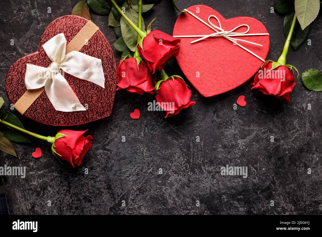 Celebration concept for Saint Valentines day or birthday with hearth shaped gift box and bouquets of red rose Stock Photo