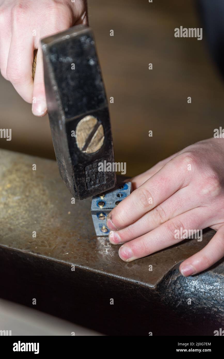 Metal worker with hammer and metal on anvil - detail Stock Photo