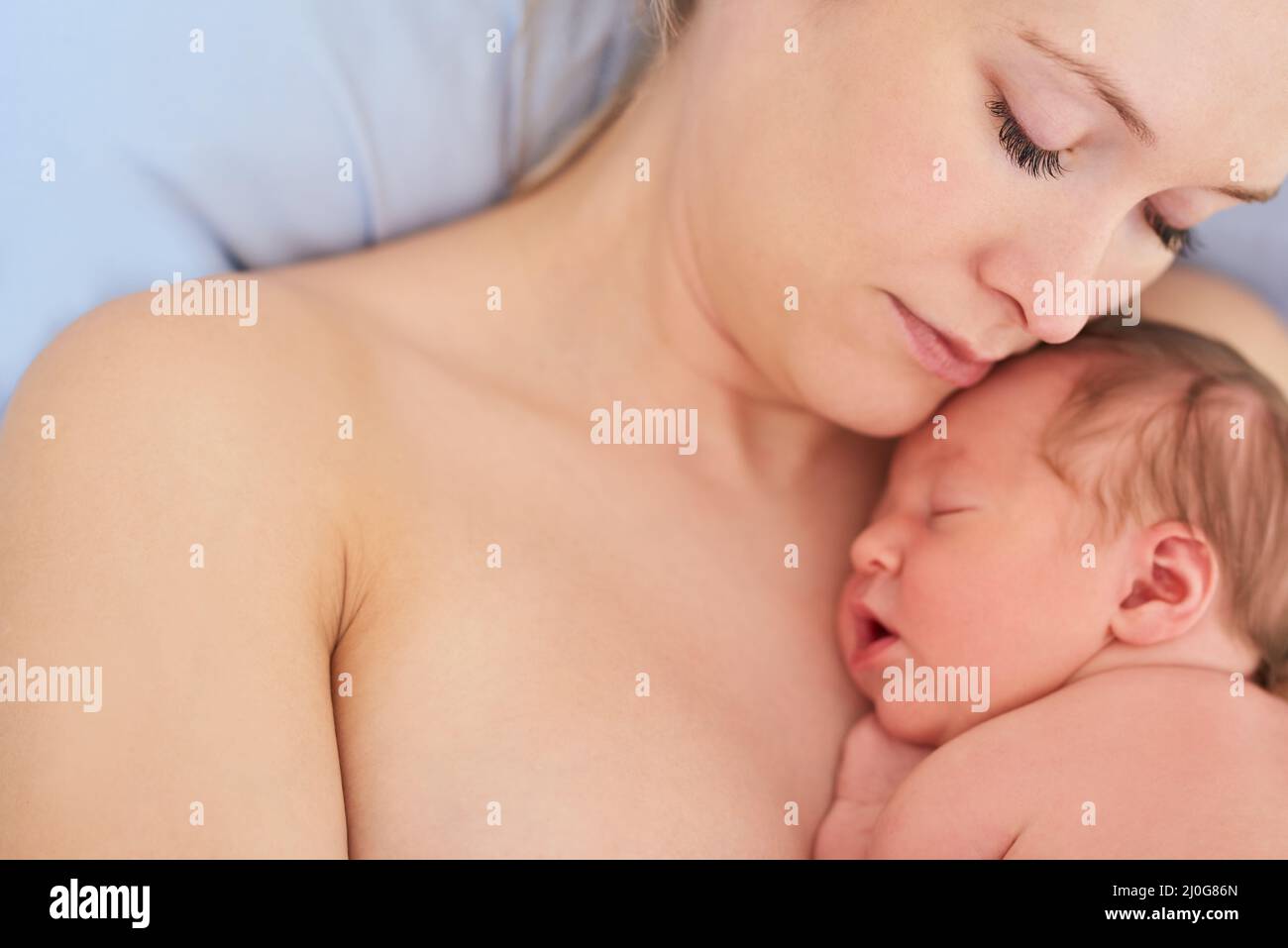 She just makes my heart melt. Shot of a beautiful young mother and her newly born baby girl sleeping in a hospital bed together. Stock Photo