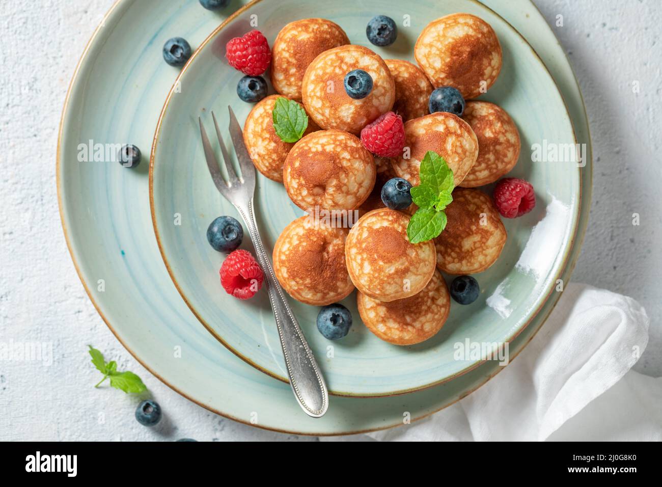 Tasty and hot poffertjes as a Danish breakfast. Poffertjes with fruits as sweet breakfast. Stock Photo