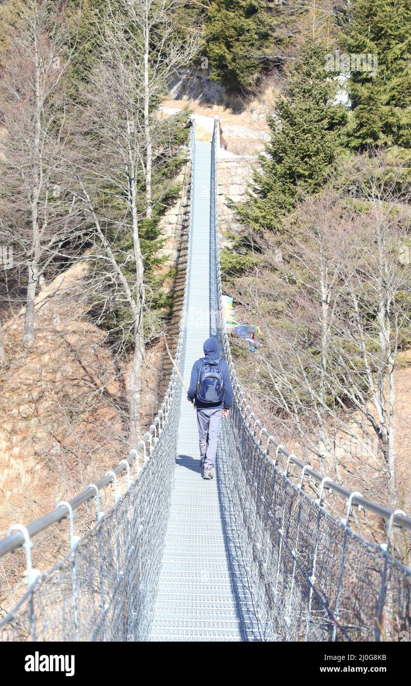 man walks on the suspension bridge in stainless steel  in Northern Italy Stock Photo