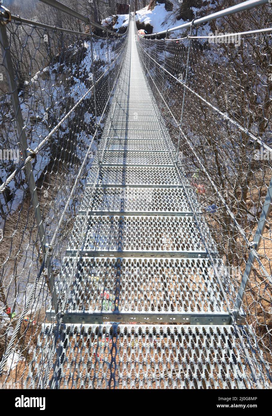 long suspension bridge in stainless steel without people in mountain in winter season Stock Photo