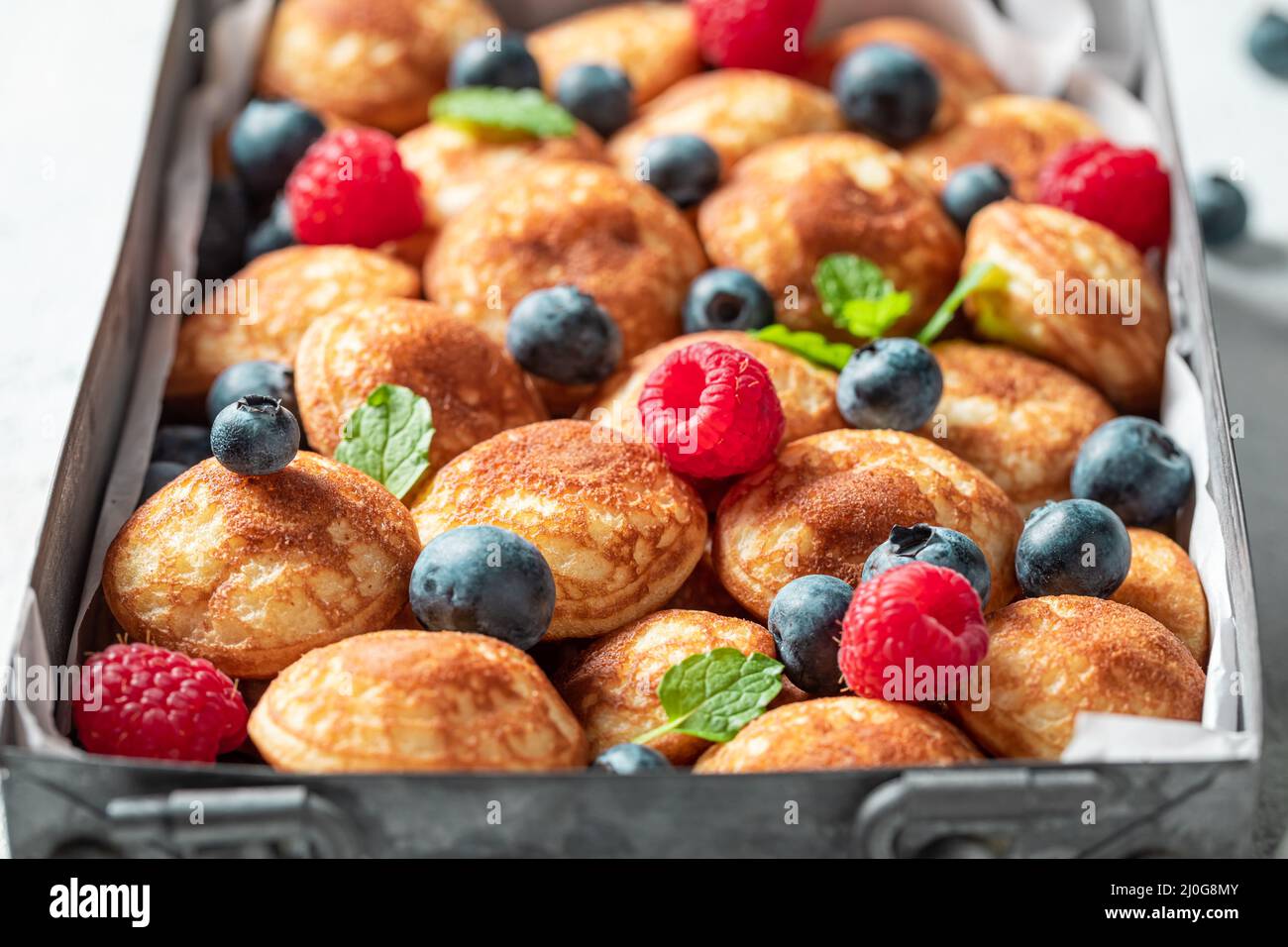 Dutch and sweet mini pancakes as a Danish breakfast. Poffertjes with fruits as sweet breakfast. Stock Photo