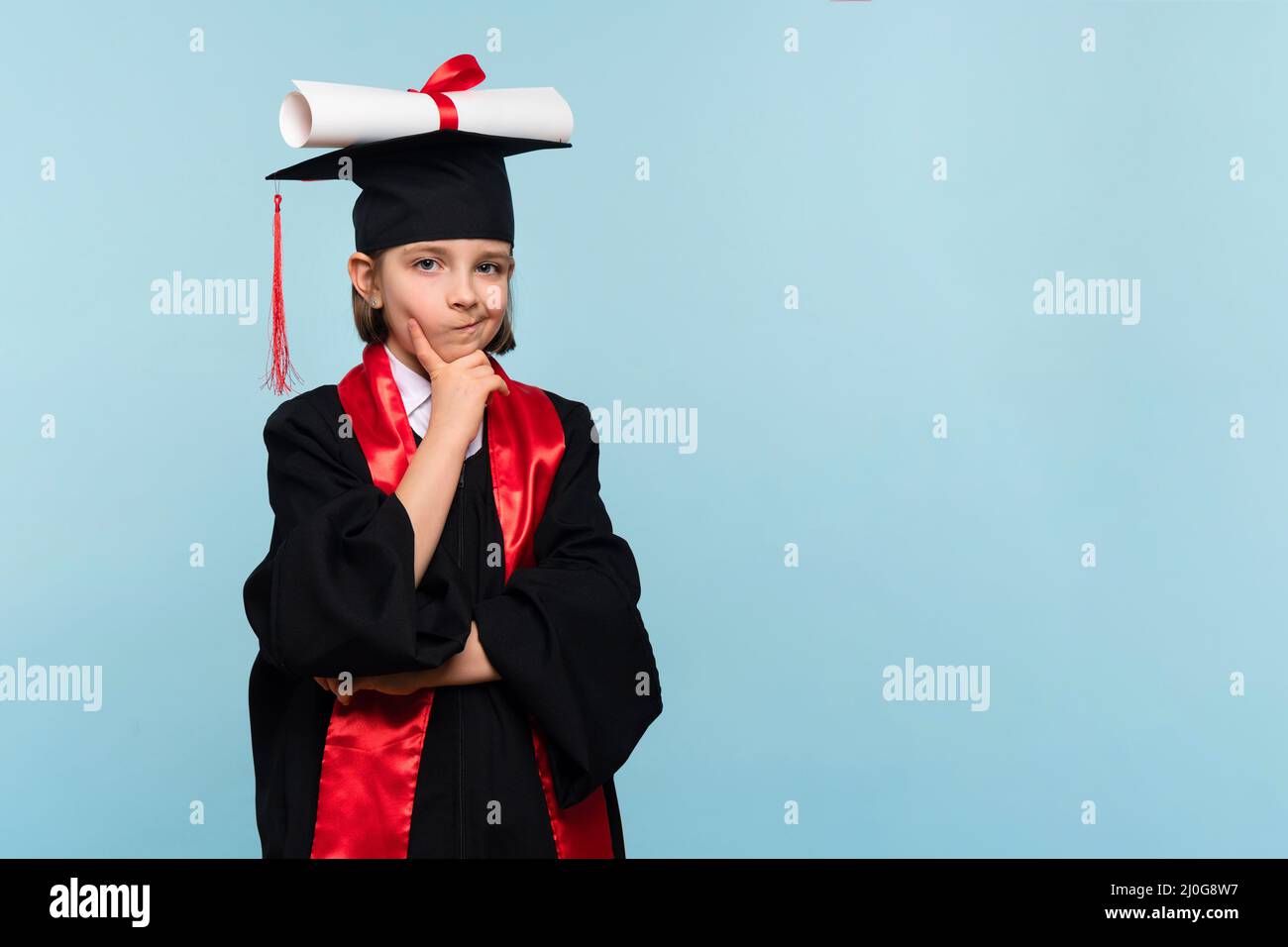 Pensive Whizz kid girl wearing graduation cap and ceremony robe with certificate diploma on