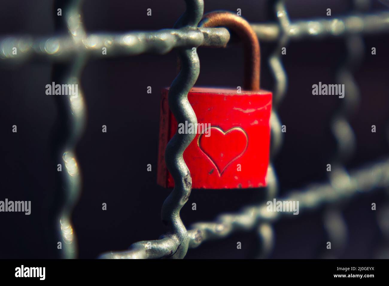 Closeup of a red love lock with an engraved heart on a bridge railing ...