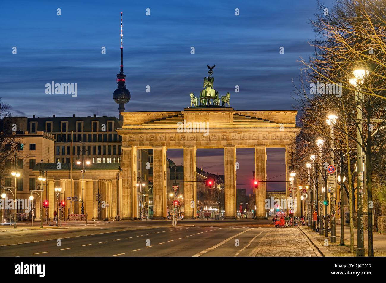 The famous Brandenburg Gate in Berlin with the Television Tower at dawn Stock Photo