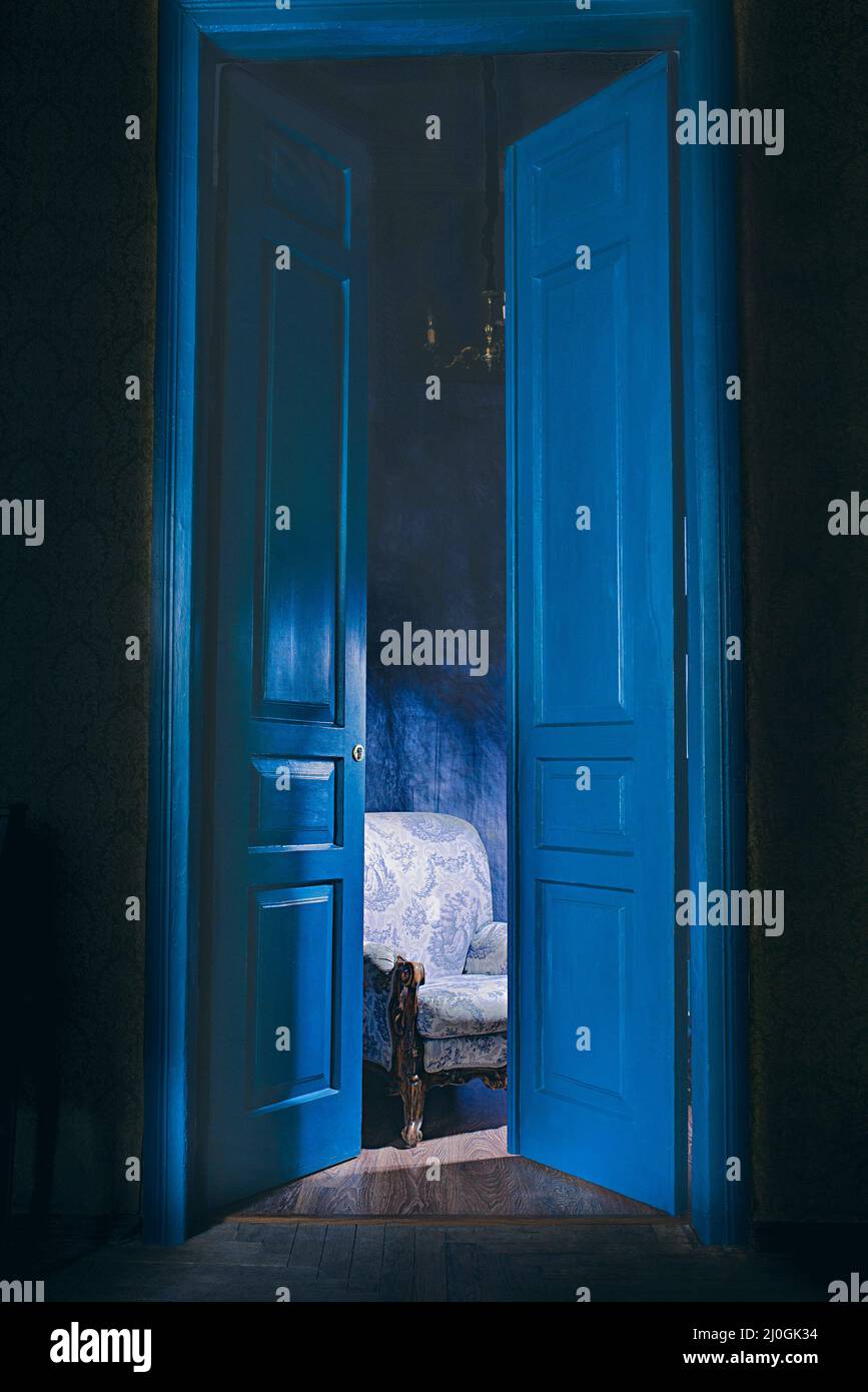 empty armchair in light behind blue massive vintage doors indoor. Old fashioned interior concept Stock Photo