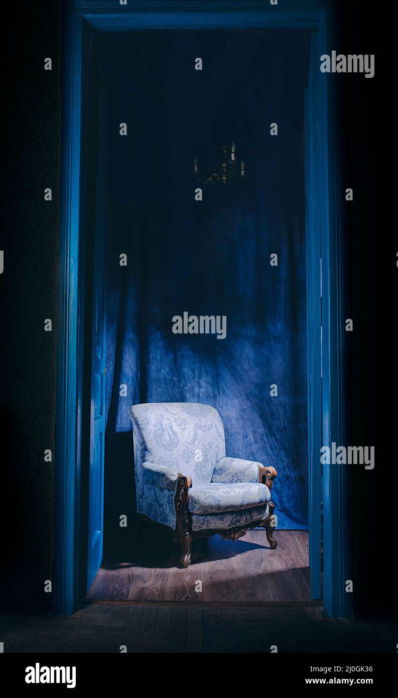 empty armchair in light behind blue massive vintage doors indoor. Old fashioned interior concept Stock Photo