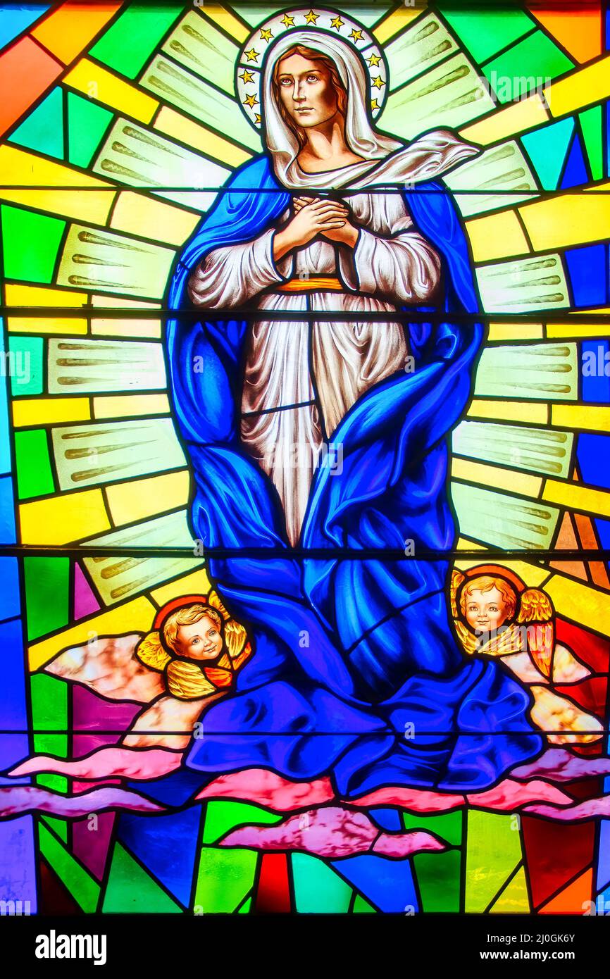 Virgin Mary stained-glass window with Christian religious symbols seen in the Annunciation of the Blessed Virgin Mary Catholic Church Stock Photo