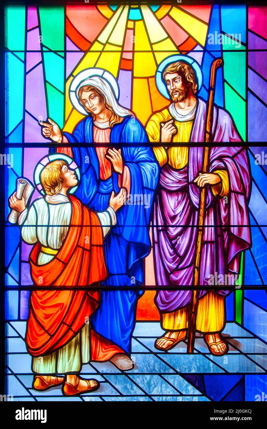 Young Jesus Christ with Mary and Joseph. Stained-glass window with Christian religious symbols seen in the Annunciation of the Blessed Virgin Mary Cat Stock Photo