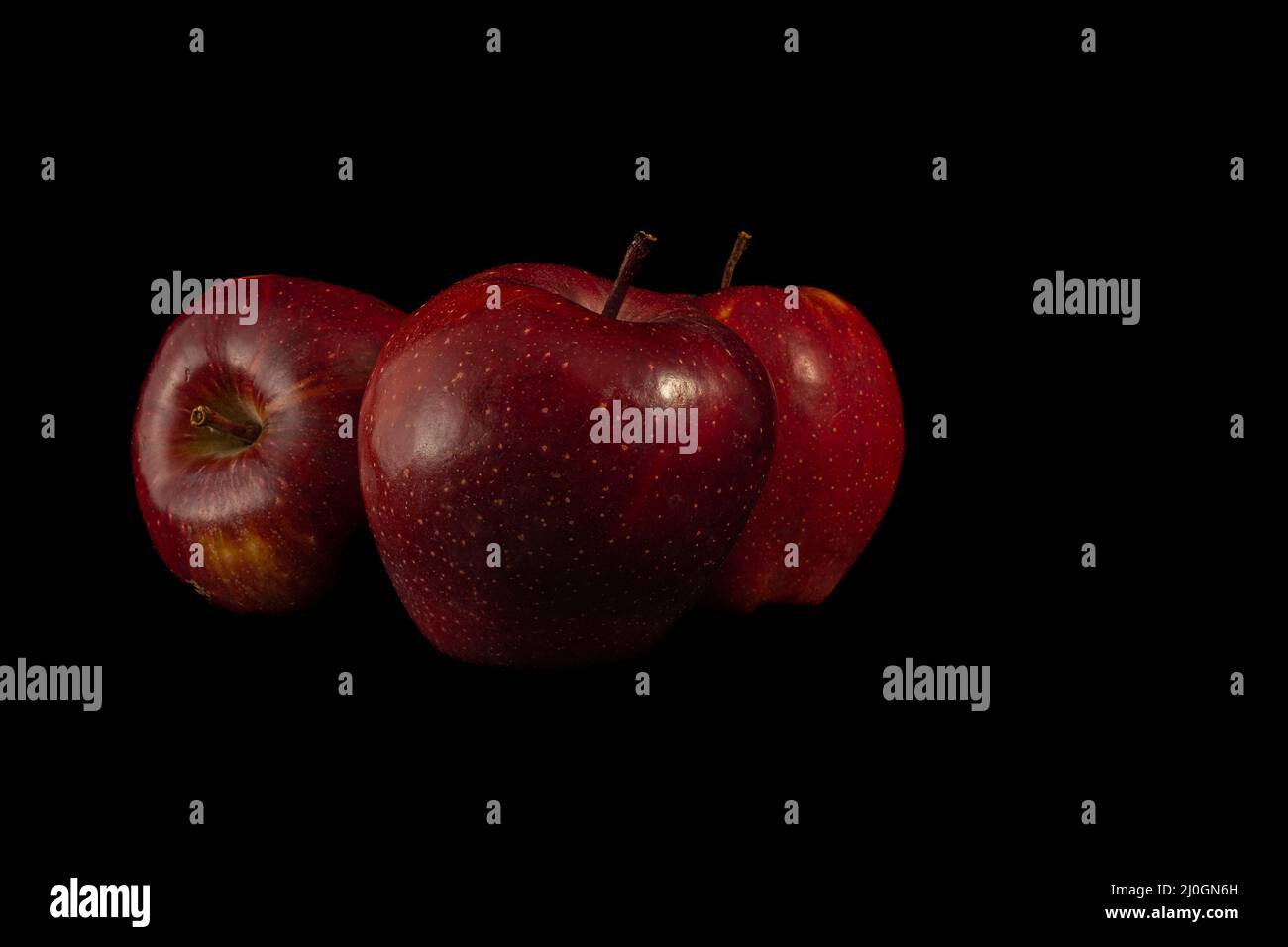 Three juicy red apples on a black background. Stock Photo