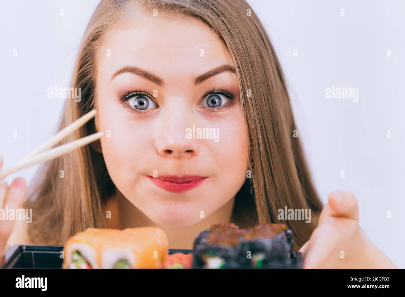 Cute white girl surprised to taste Japanese sushi for the first time, close-up Stock Photo