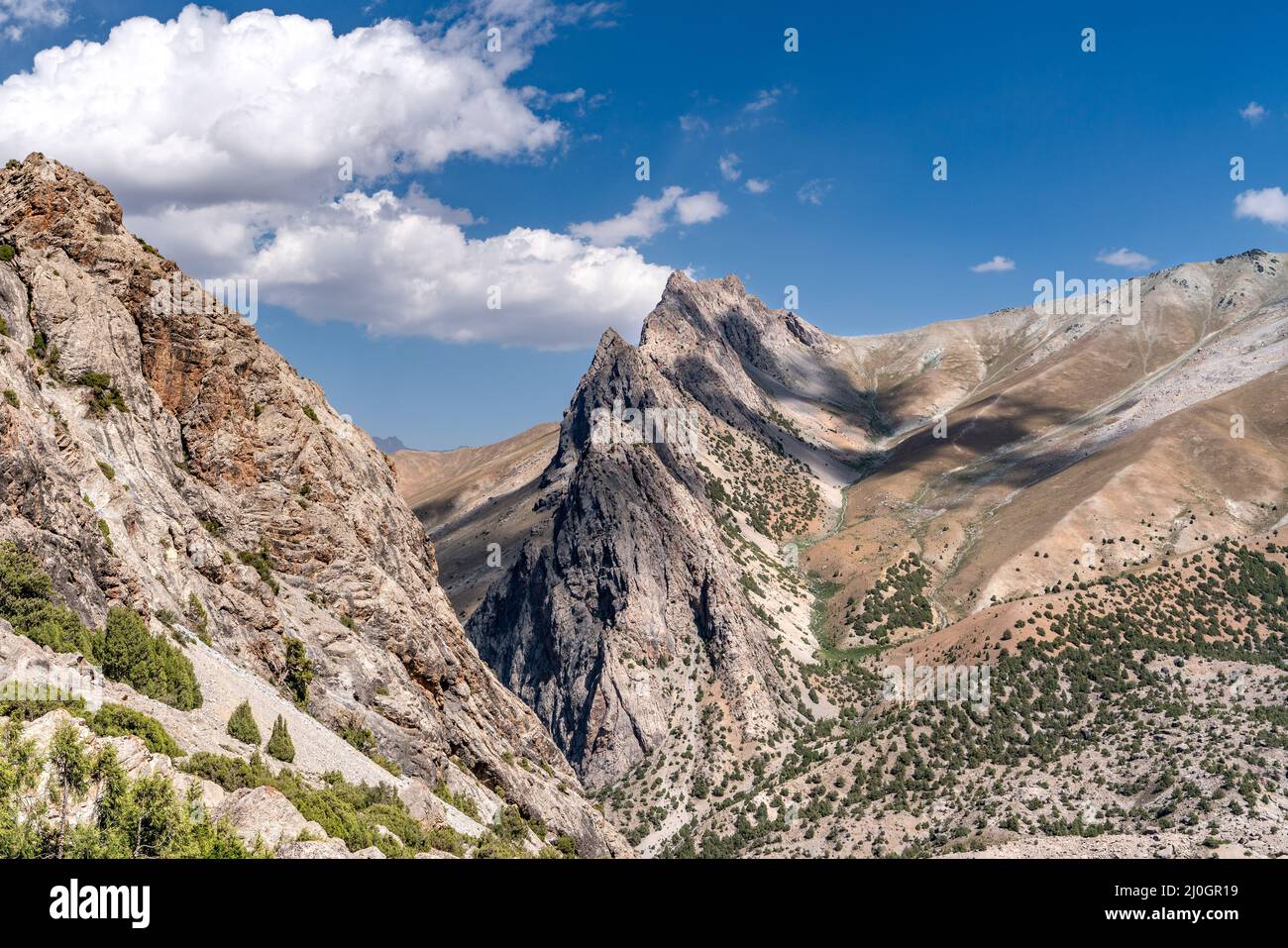 The beautiful mountain trekking road with clear blue sky and rocky hills and the view of Alaudin lake in Fann mountains in Tajik Stock Photo
