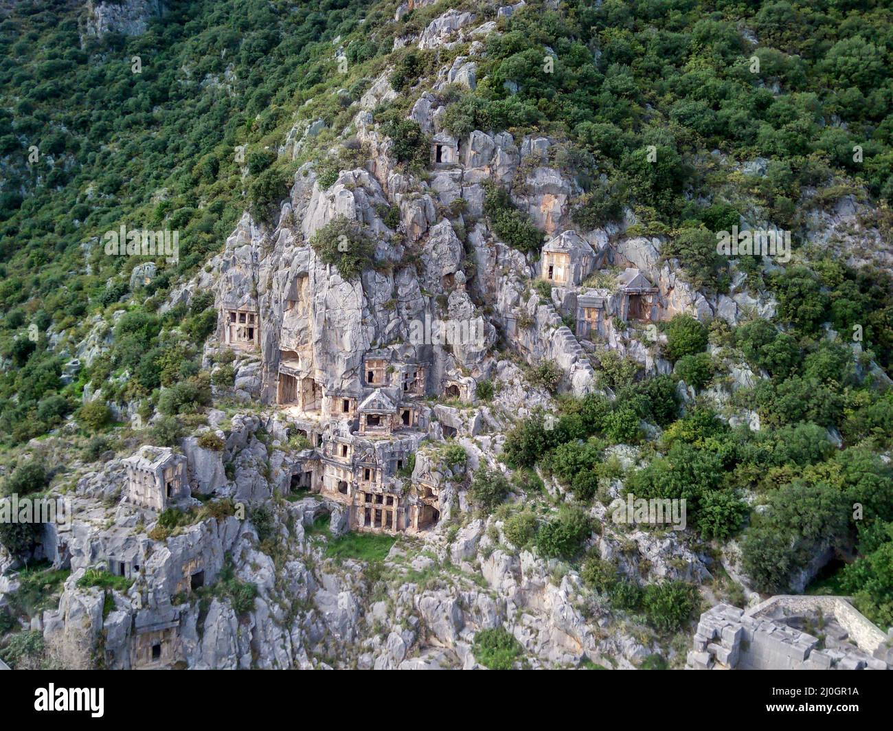 High angle drone aerial view of ancient greek rock cut tombs carved into cliffside in Myra (Demre Stock Photo