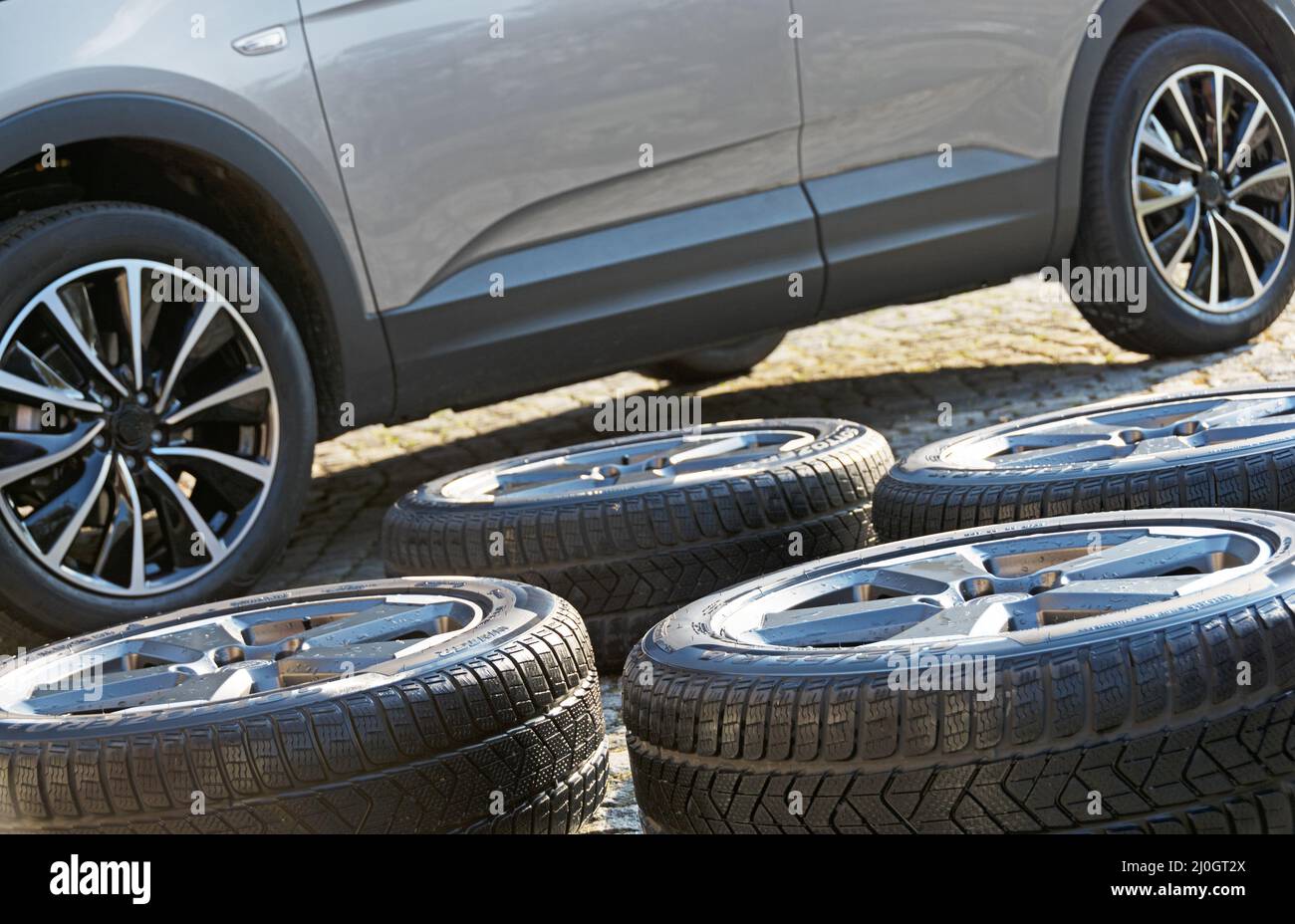 Washed winter wheels in front of modern car with summer wheels Stock Photo