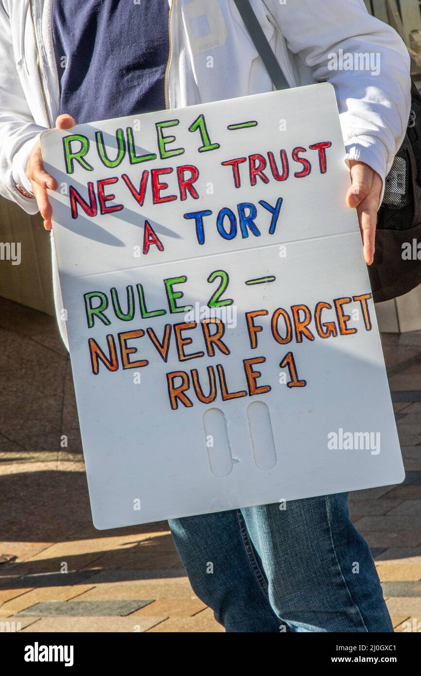 Rukle 1 Never Trust a Tory placard in Blackpool, Lancashire.UK 19 March 2022; Boris Johnson will return to Blackpool Winter Gardens, for the Conservative Party's Spring Conference. The delegates' arrival for two days of speeches and debate will be the most high-profile event at the new complex since the renovations were completed. requirements.  Anti-Tory Protestors & campaigners gather on the seafront promenade with flags, trade union banners, placards, publications & hand written signs to protest against the Tory Government. Credit MediaWorldImages/AlamyLiveNews Stock Photo