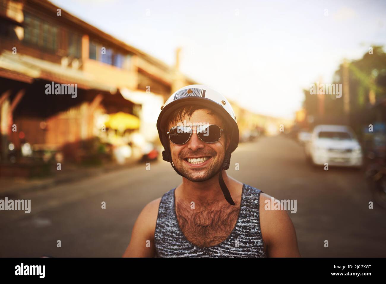 Happy smiling and screaming male tourist in helmet and sunglasses riding motorbike  scooter during his tropical vacation under palm trees Stock Photo - Alamy