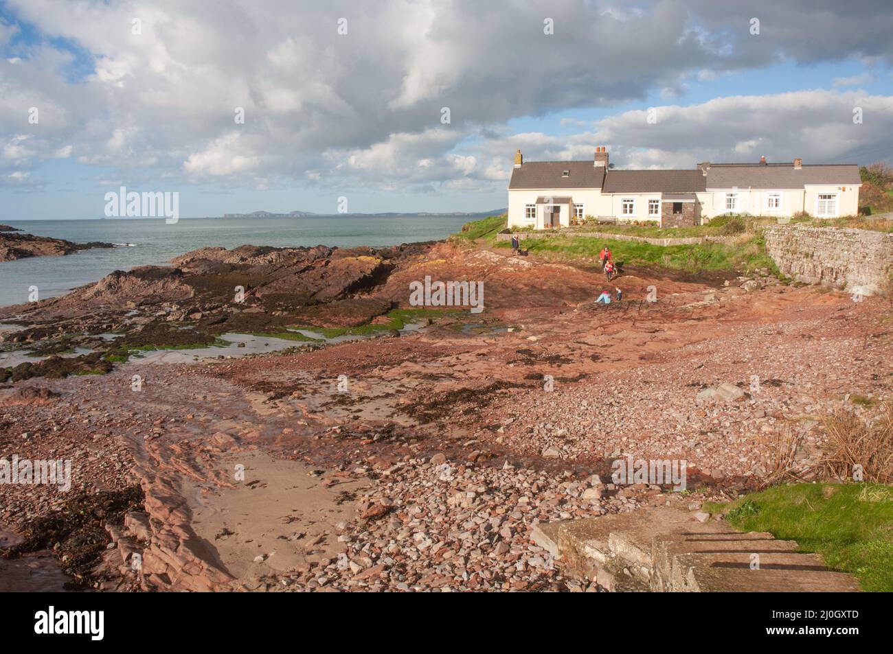 Family walking on coastal path and cove at St Brides HAven ...