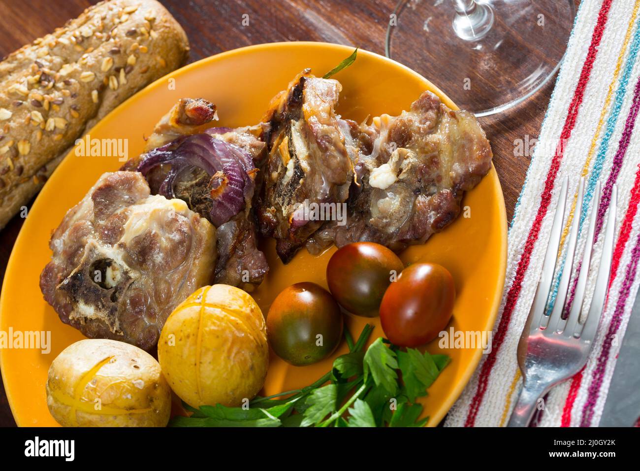 Baked lamb leg chops with potatoes, tomatoes, greens Stock Photo - Alamy