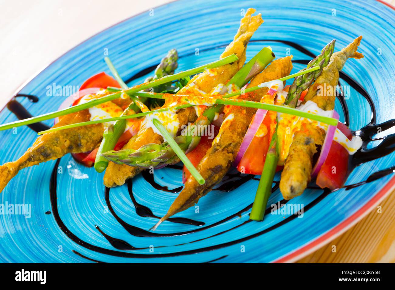 Fried sardines in batter and creamy-ginger sauce, sweet tomatoes and balsamic paste Stock Photo
