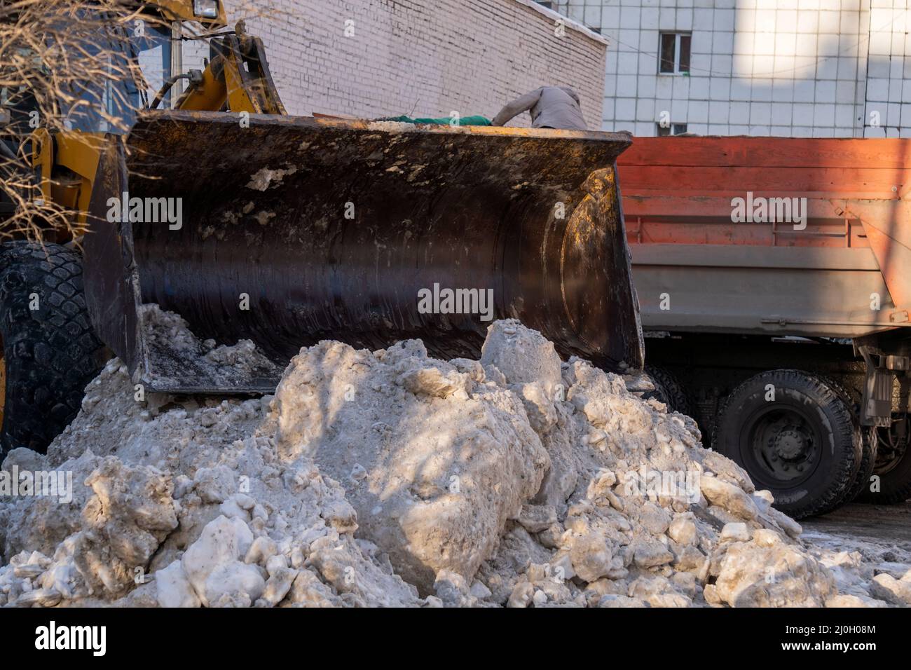 Bulldozer rakes up pieces of ice after a snowfall. Snow removal from