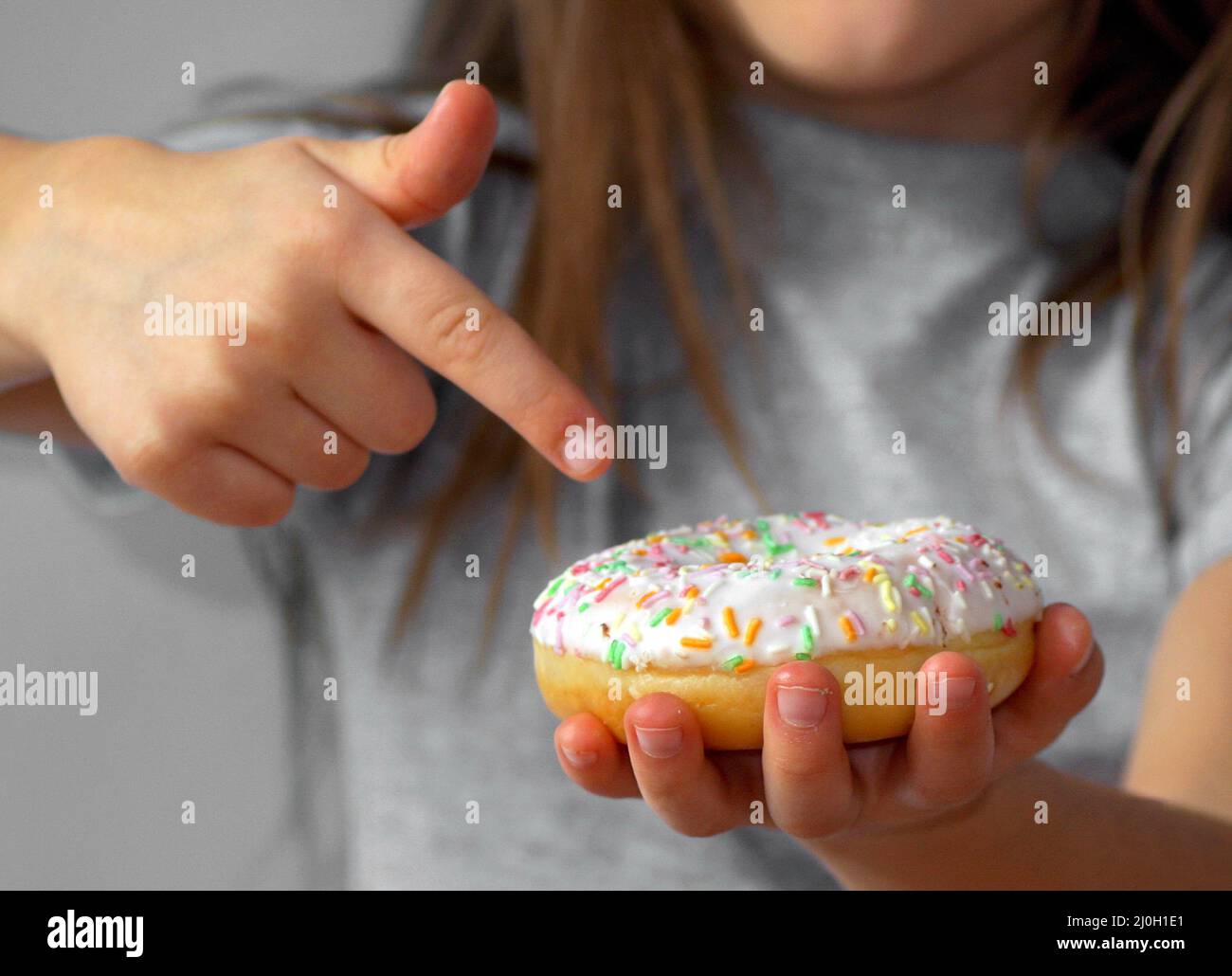 The girl points a finger at the donut, says that it is very tasty, it is the best Stock Photo