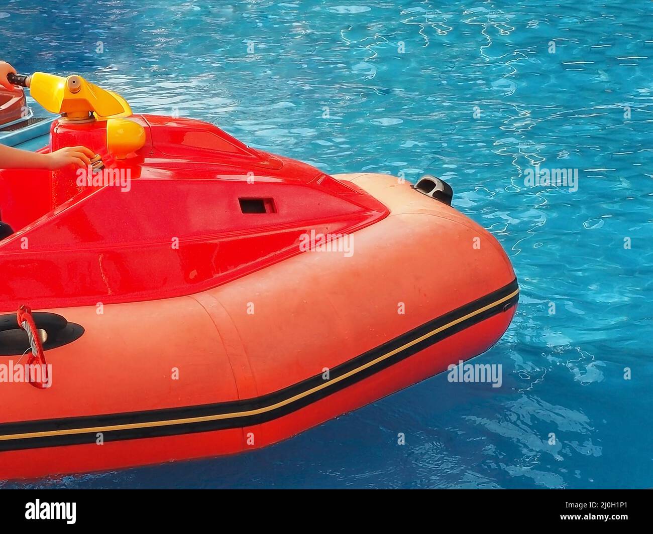 Fragment of a children's red inflatable boat floating in a blue outdoor pool Stock Photo