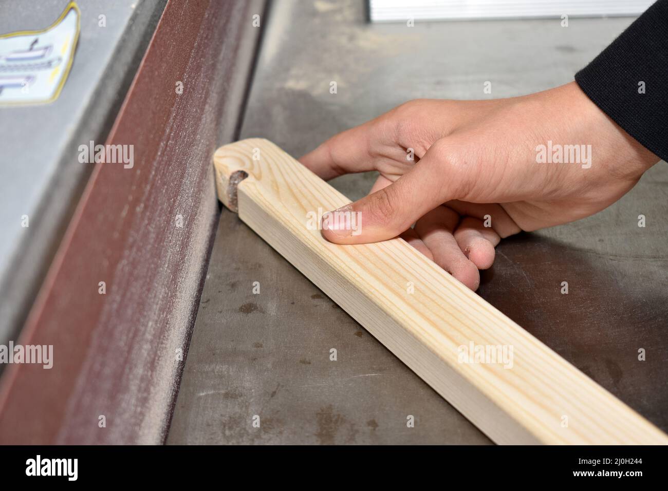 Carpenter grinds on a belt sander closeup craftsman Stock Photo Alamy