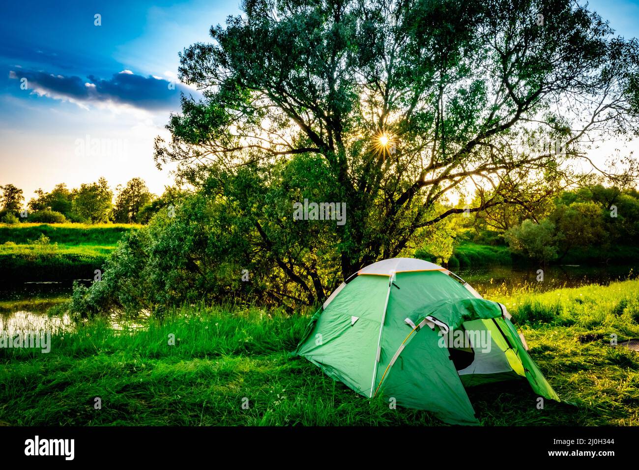 Green tourist tent by the river at sunset Stock Photo - Alamy