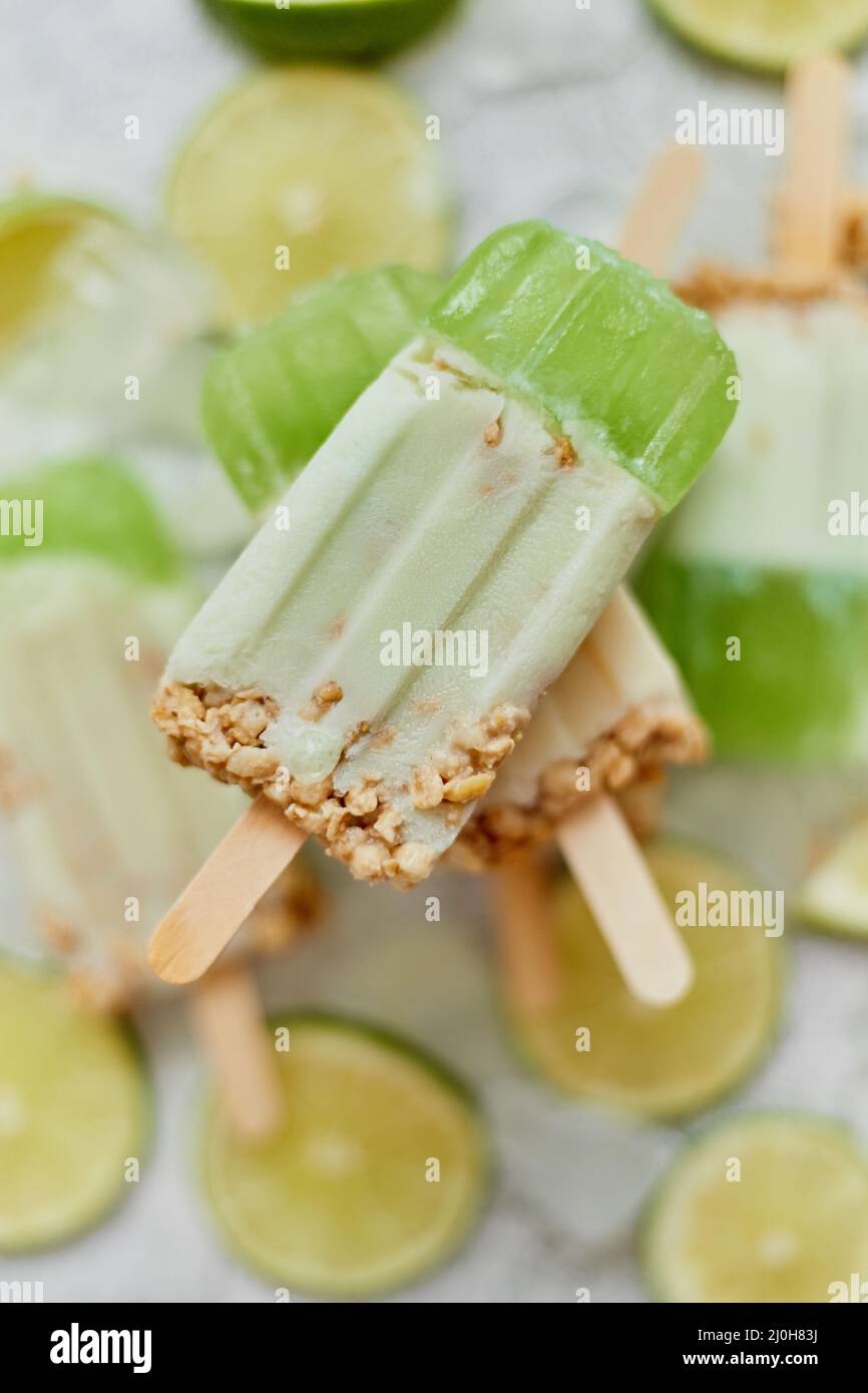 Close up on kid's hand holding colorful lime and cream popsicle Stock Photo