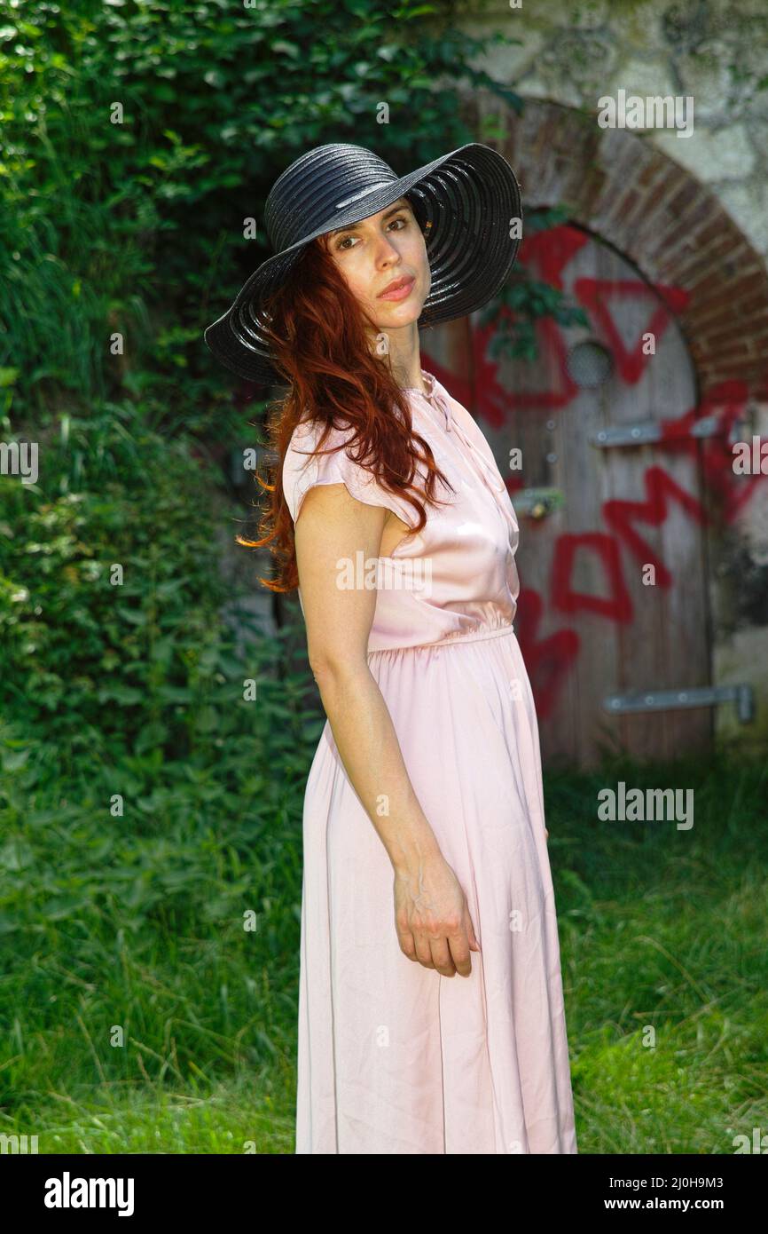 young woman in casual dress; in overgrown backyard Stock Photo