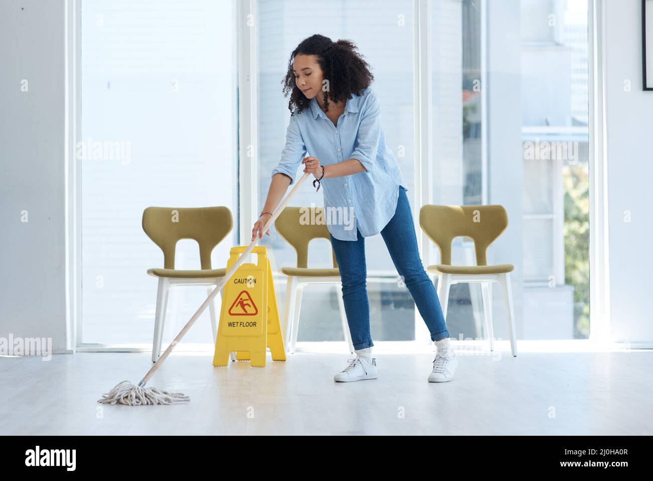 Nothing like seeing your floors sparkle. Shot of a young woman mopping her floor at home. Stock Photo
