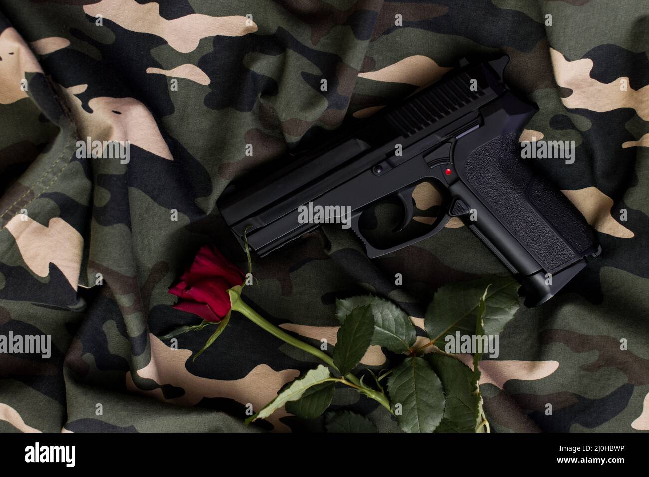 Top view, black handgun and red rose on military uniform Stock Photo