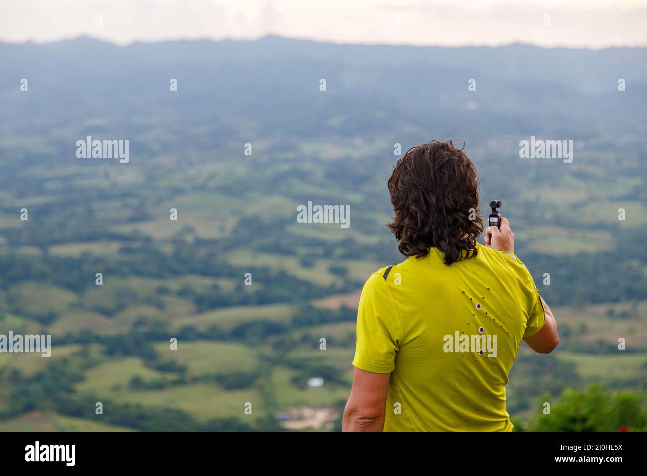 A man stands on a mountain and shoots a video on a modern miniature camera. Stock Photo