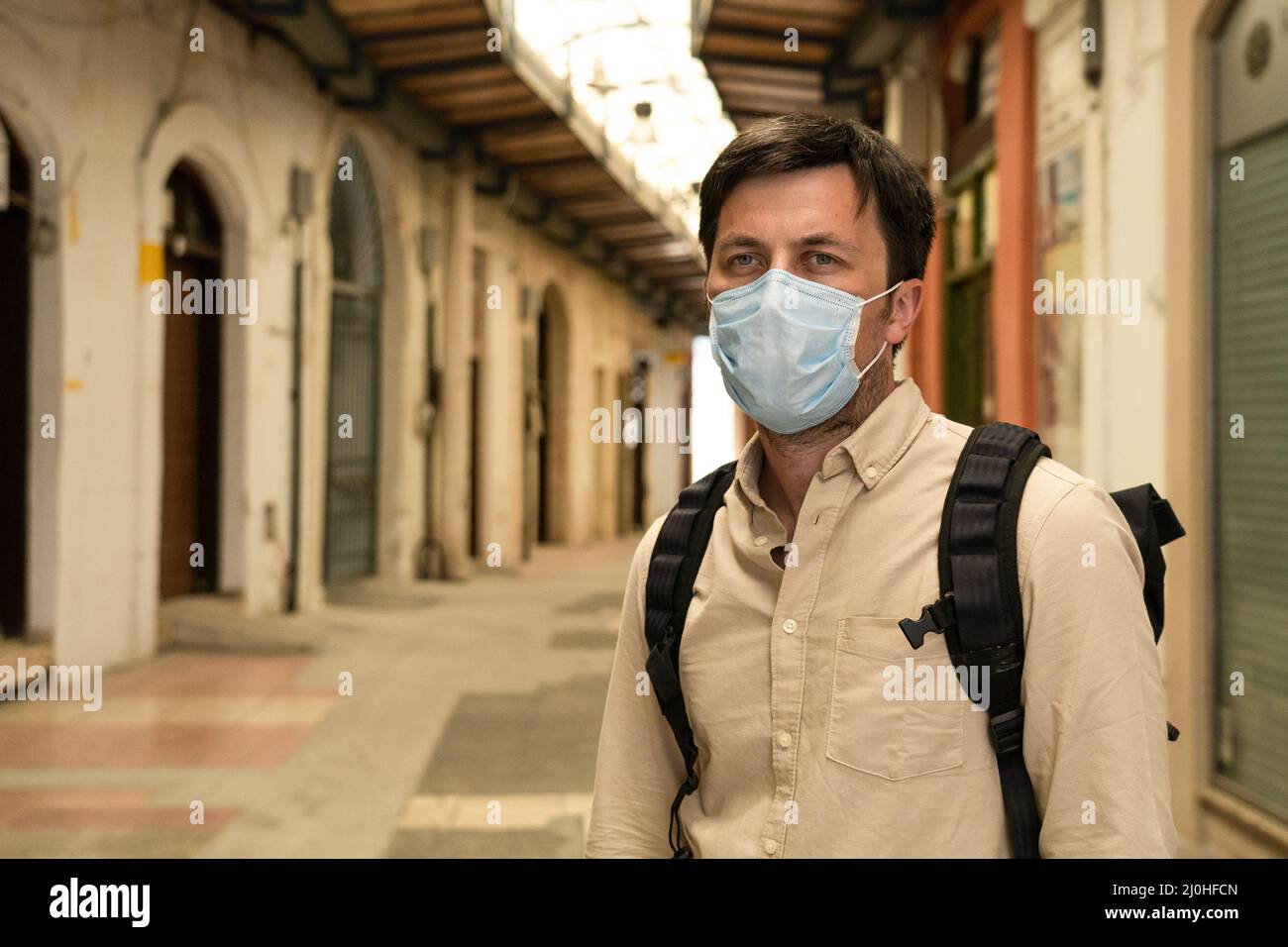 Masked male tourist walks at closed market during coronavirus pandemic, lockdown on Cyprus. Man in mask walks through market in Stock Photo