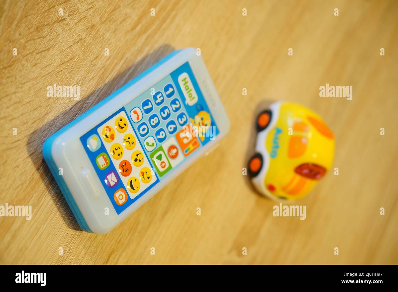 Fisher-Price brand toy telephone next to a V Tech car with sounds on a wooden tab Stock Photo