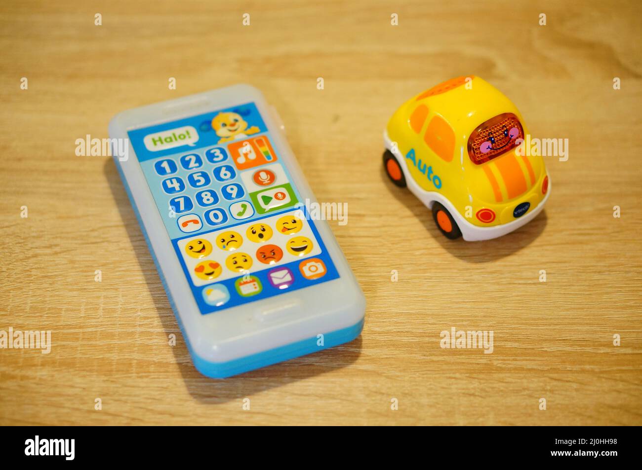 Fisher-Price brand toy telephone next to a V Tech car with sounds on a wooden tab Stock Photo
