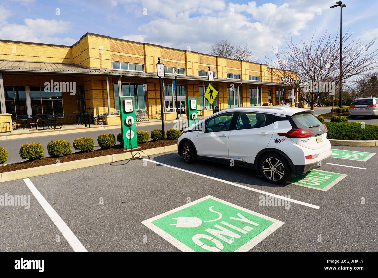 Lancaster, PA, USA - March 18, 2022: An EV charging station in the parking lot of a grocery store allows costumes to recharge their eclectic car while Stock Photo