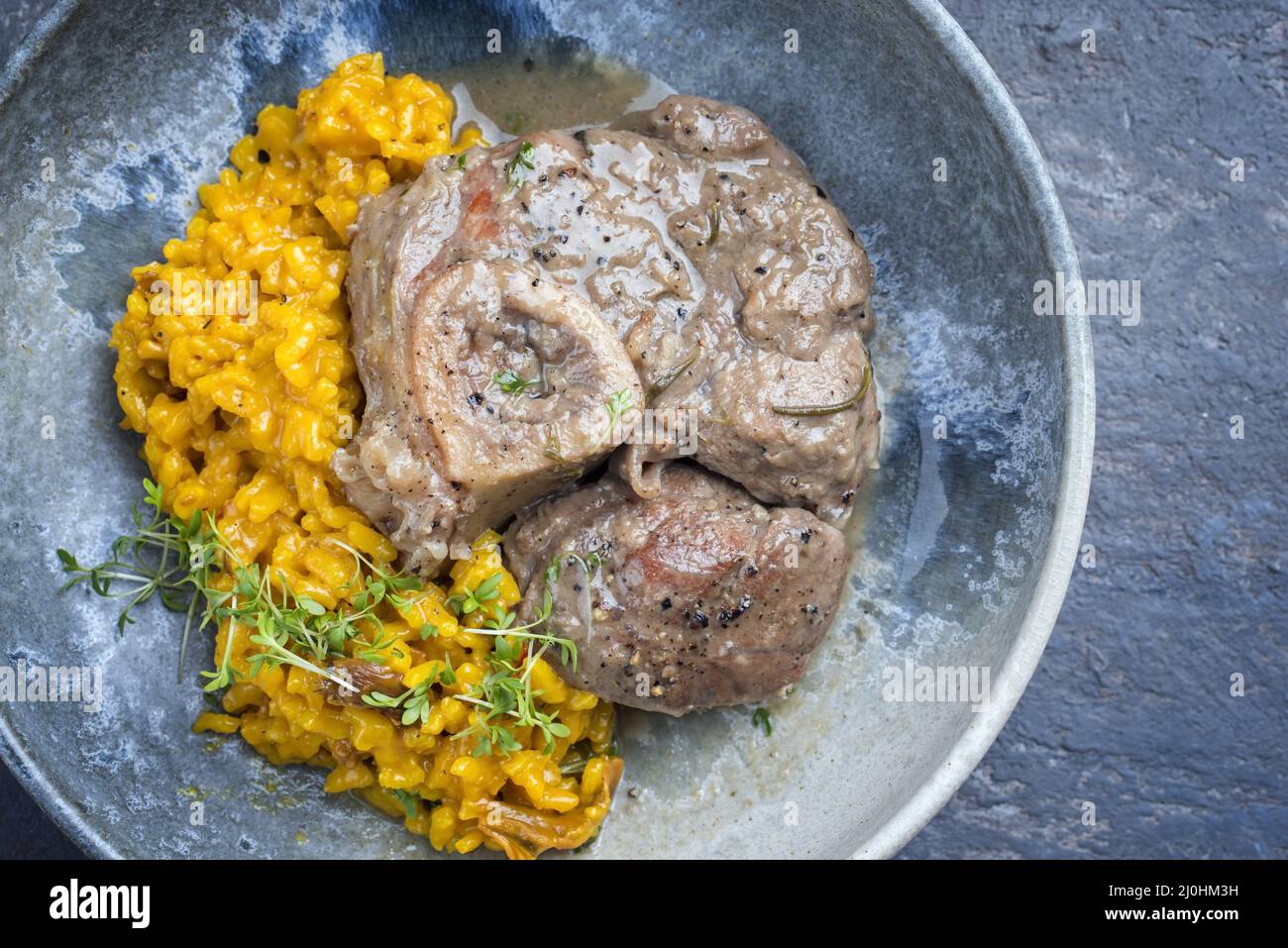 Modern style traditional braised Italian ossobuco alla Milanese with saffron risotto and baby broccoli in white wine meat sauce Stock Photo