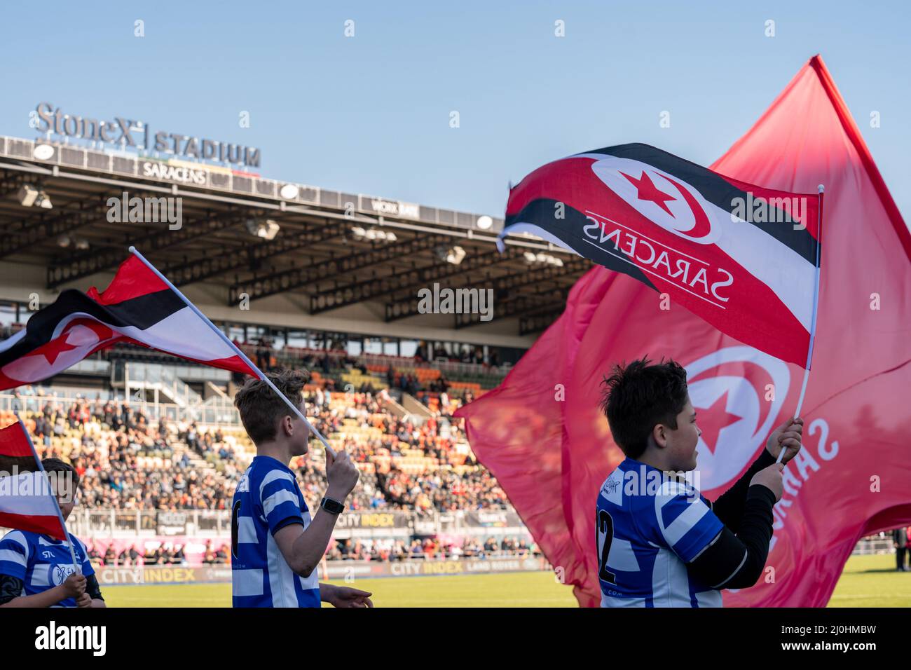 Junior Rugby Clubs wave their flags to welcome the Saracens players onto the pitch Stock Photo